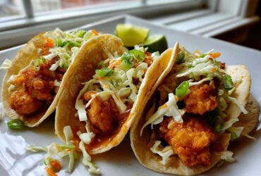 Three Crispy Baked Fish Tacos filled with golden fried fish pieces and topped with bright lime slaw.