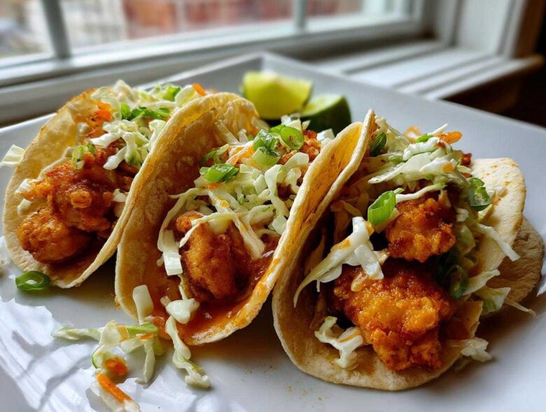 Three Crispy Baked Fish Tacos filled with golden fried fish pieces and topped with bright lime slaw.