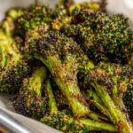 Close-up of deeply roasted, dark green broccoli florets coated in crispy Parmesan cheese.