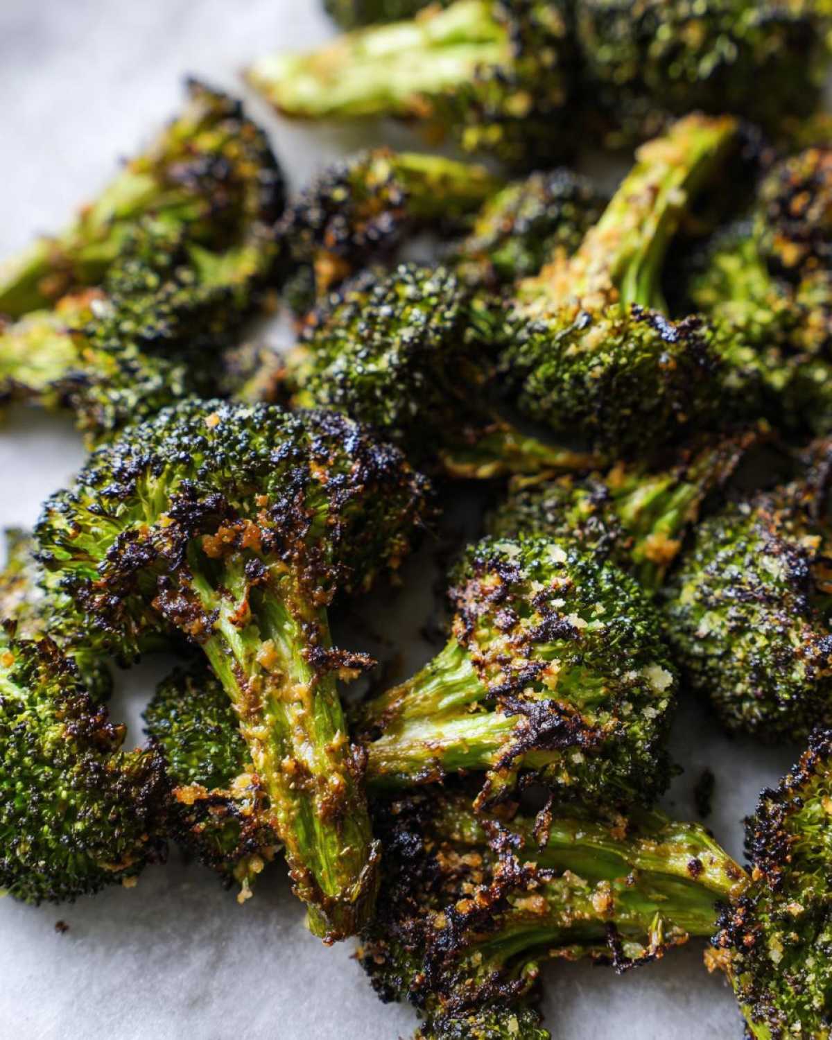 Extreme close-up of deeply roasted, crispy Parmesan roasted broccoli florets showing charred edges and cheesy coating.