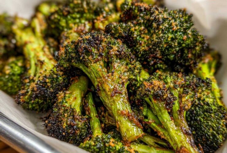 Close-up of deeply roasted, dark green broccoli florets coated in crispy Parmesan cheese.