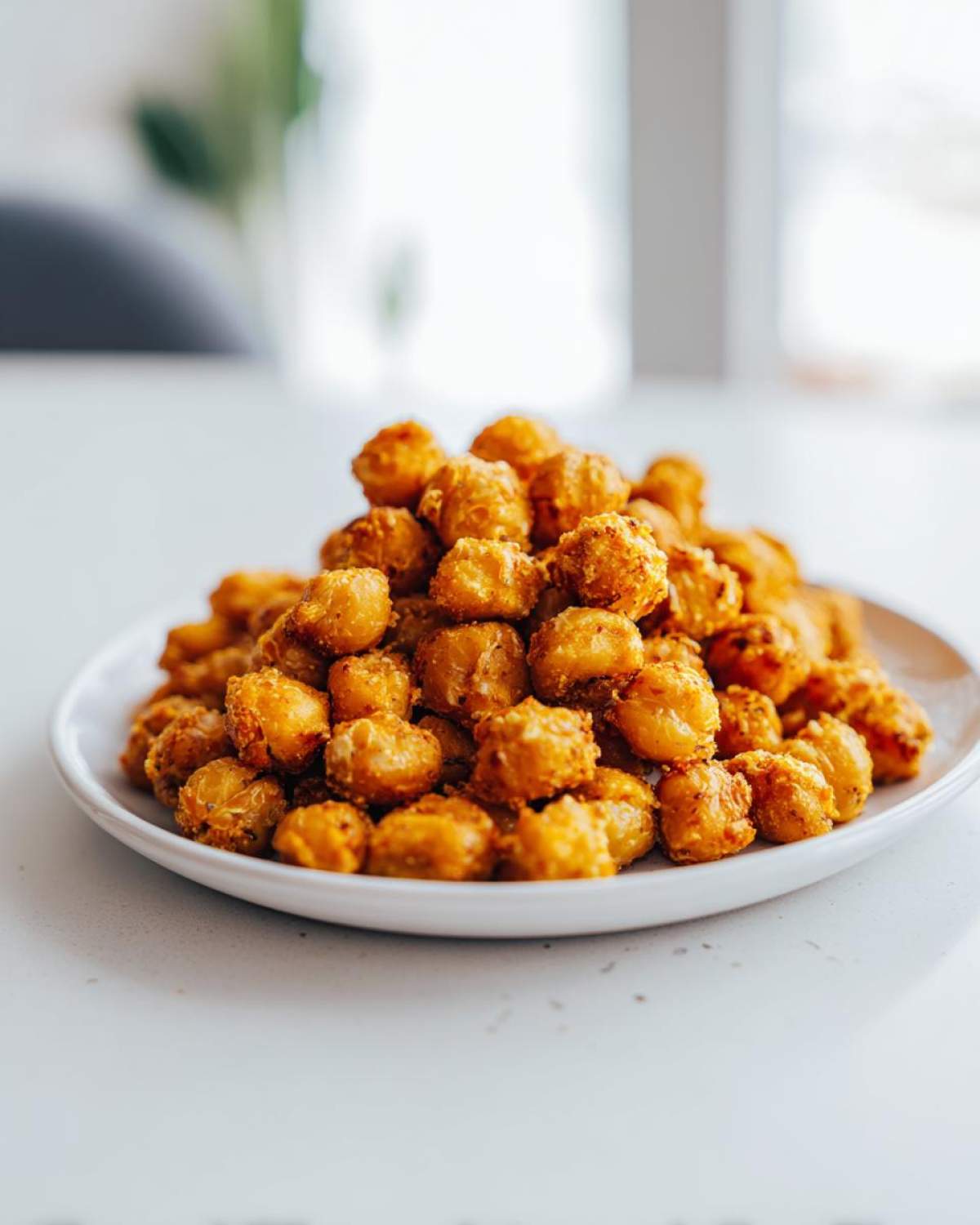 A mound of golden brown, seasoned Crunchy Air Fryer Ranch Chickpeas piled high on a white plate.