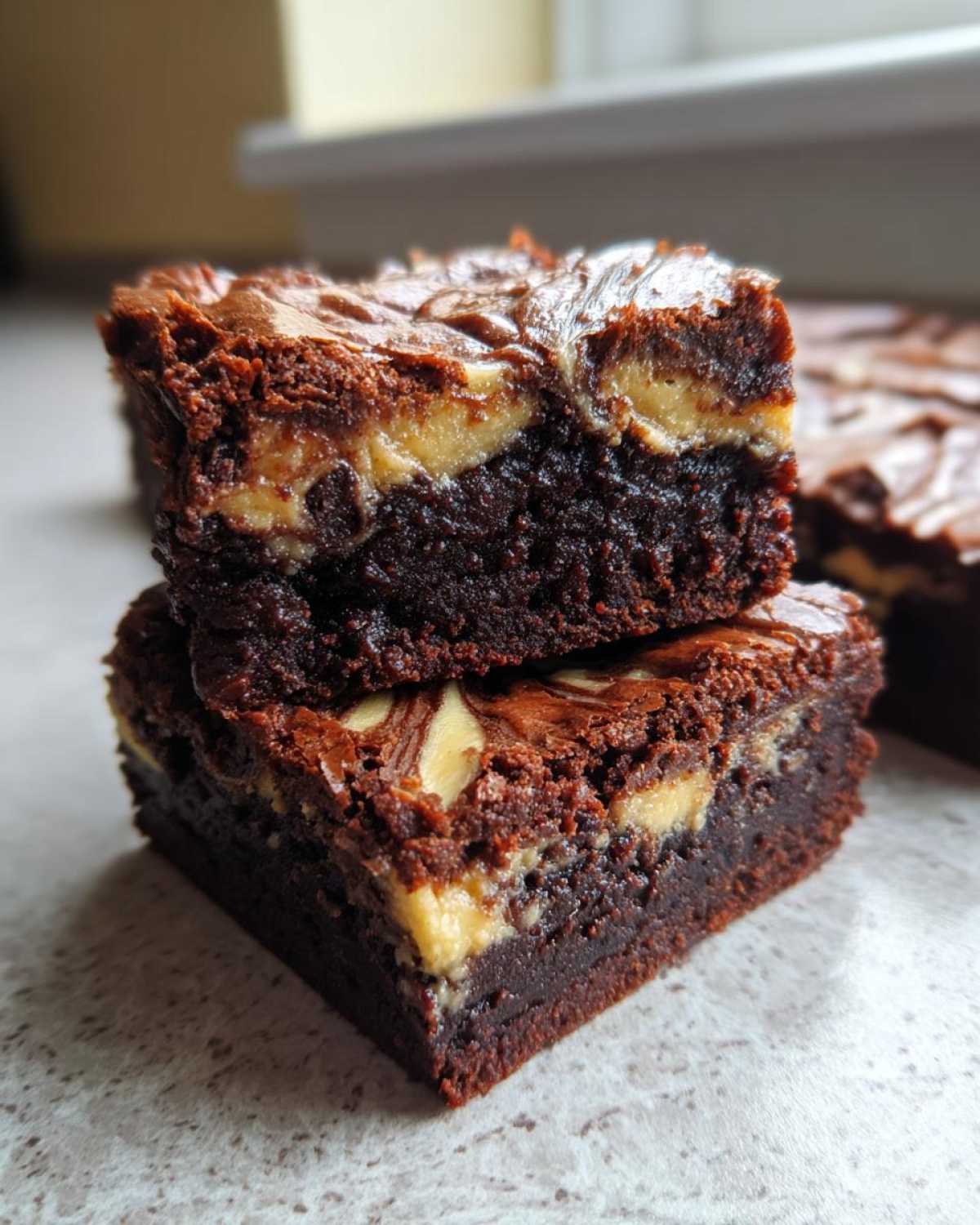 Two stacked, fudgy Dark Chocolate Tahini Brownies showing a creamy tahini swirl layer inside.