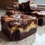 A rich, fudgy square of Dark Chocolate Tahini Brownies showing a swirl of tahini filling.