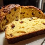 Close-up of a golden-brown loaf of Easy Irish Soda Bread with Buttermilk and Raisins, showing a thick slice cut from the front.