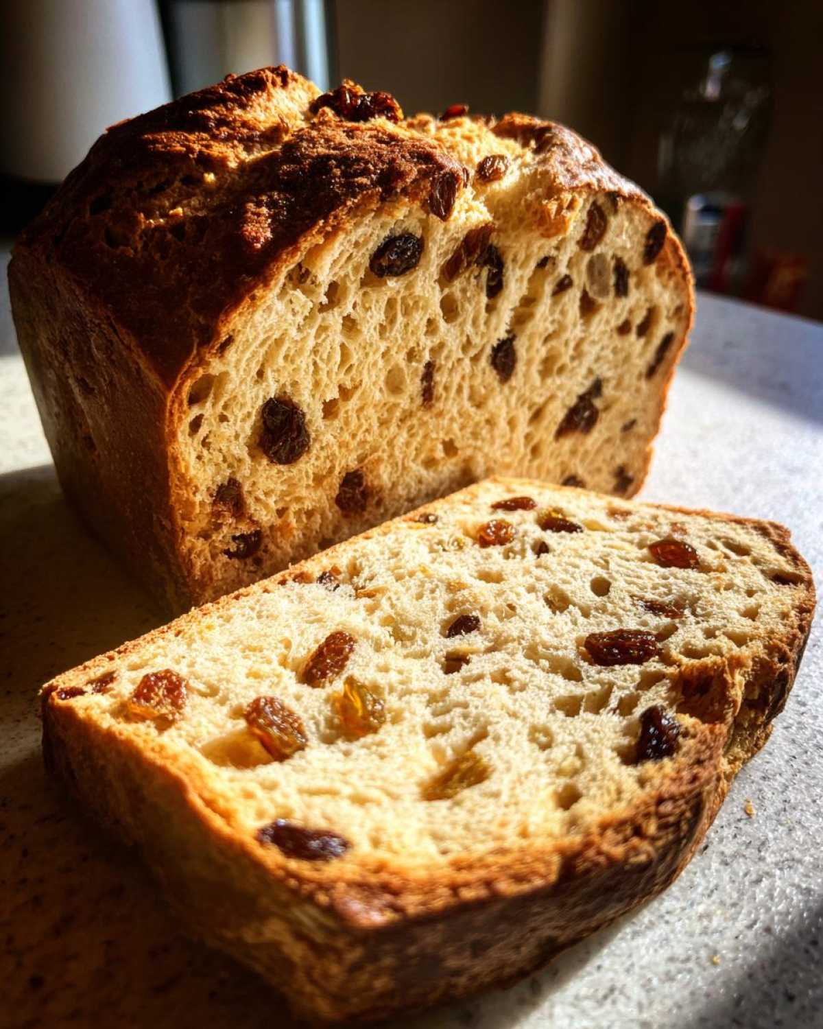 A loaf of Easy Irish Soda Bread with Buttermilk and Raisins, sliced to show the soft interior dotted with raisins.