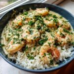 Close-up of Garlic Butter Shrimp and Rice Skillet served in a dark bowl, topped with fresh parsley.