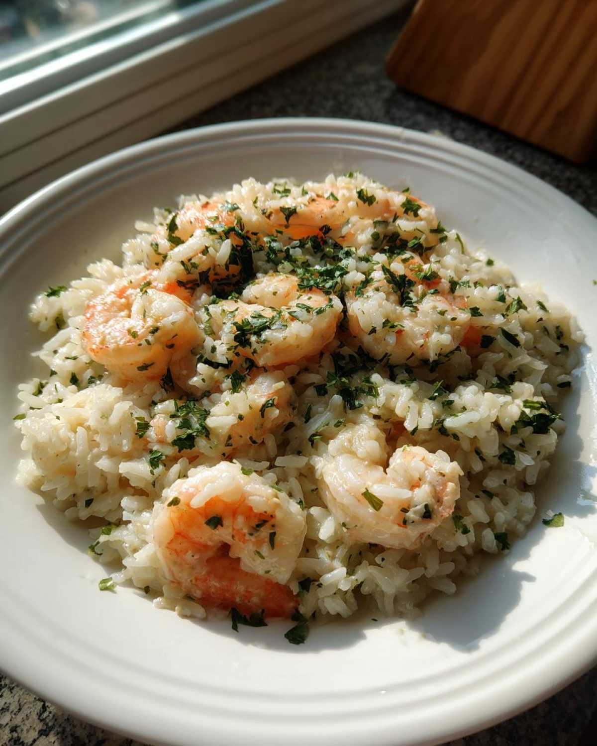 A white bowl filled with Garlic Butter Shrimp and Rice Skillet, topped with fresh parsley.