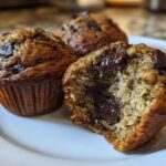 Close-up of three Gluten-Free Banana Chocolate Chip Muffins, one broken open showing melted chocolate chips inside.