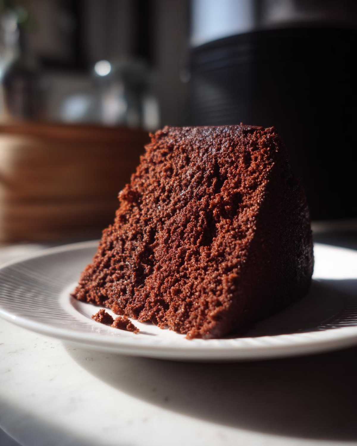 Close-up of a moist slice of Gluten-Free Chocolate Cake showing its dark, rich crumb texture on a white plate.