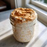 Close-up of High-Protein Peanut Butter Overnight Oats topped with swirled peanut butter in a glass jar.
