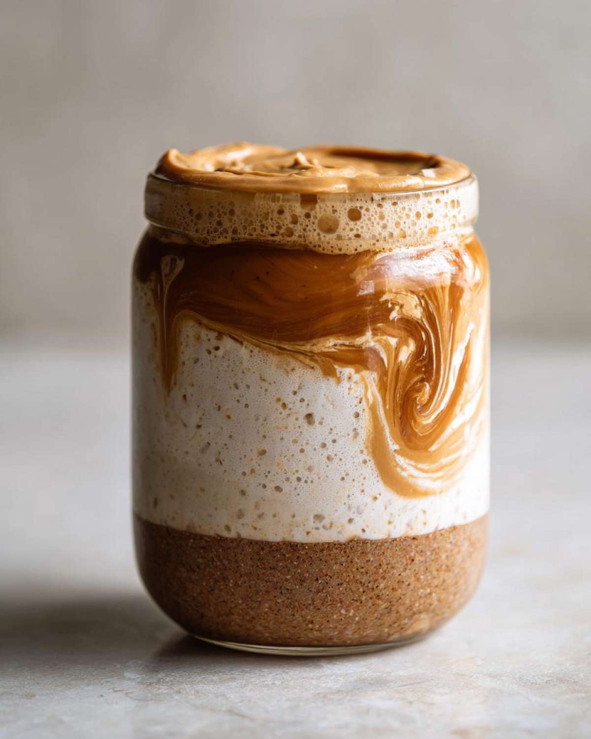 Close-up of High-Protein Peanut Butter Overnight Oats layered in a glass jar with creamy swirls.