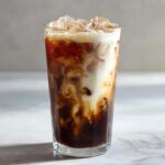 Close-up of an Iced Honey Almond Milk Latte showing rich swirls of coffee and almond milk over ice.
