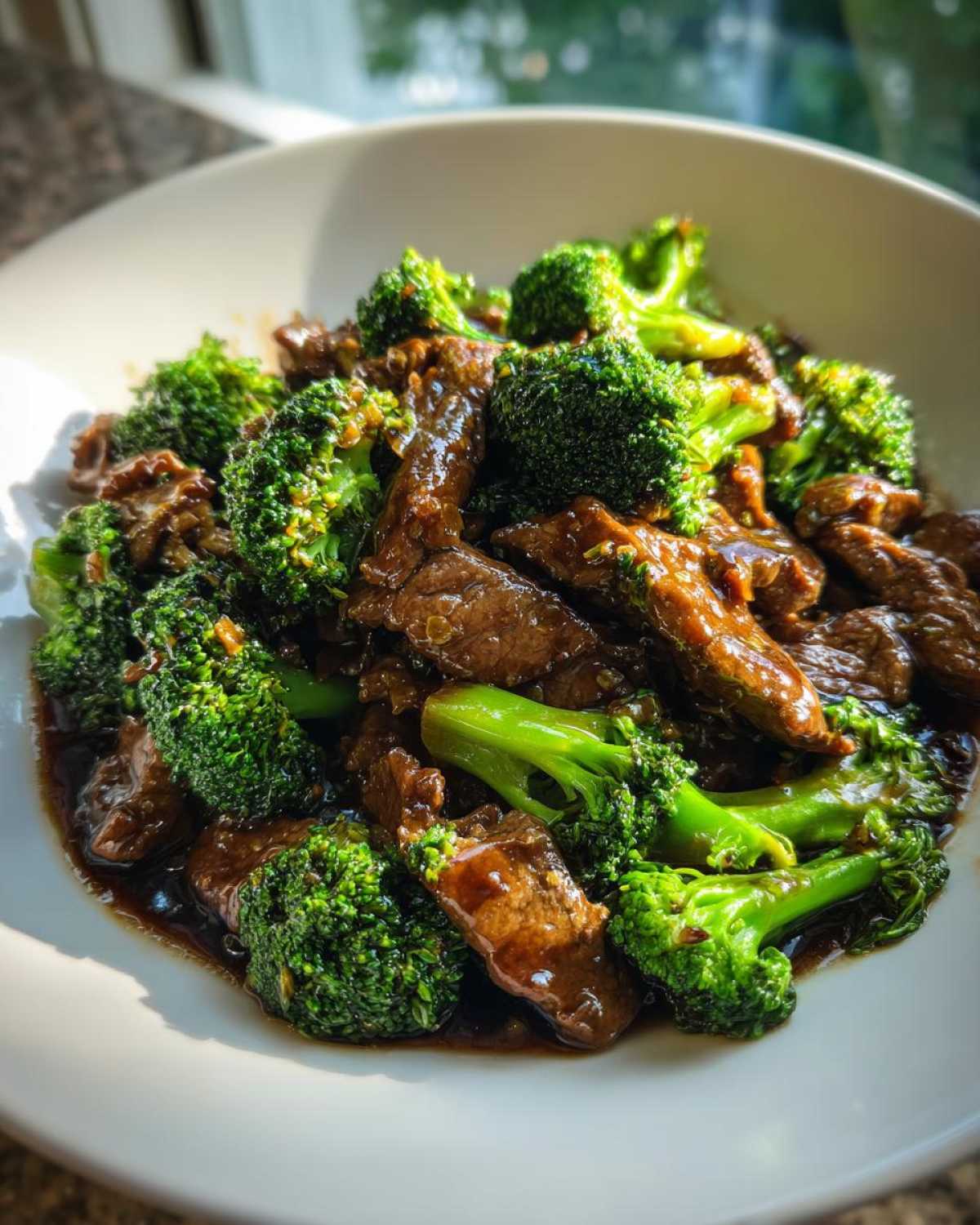 Close-up of savory Instant Pot Beef and Broccoli coated in a rich brown sauce, served in a white bowl.