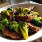 Close-up of tender slices of beef and bright green broccoli florets coated in a savory sauce, ready to eat Instant Pot Beef and Broccoli.
