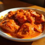 Close-up of tender chicken pieces coated in rich, vibrant orange sauce for Instant Pot Butter Chicken.