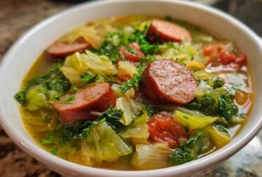 Close-up of a white bowl filled with flavorful Instant Pot Cabbage and Sausage Soup, featuring thick sausage slices and tender cabbage.
