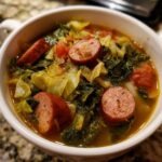 A close-up of a white bowl filled with Instant Pot Cabbage and Sausage Soup, featuring sliced sausage and cooked cabbage.