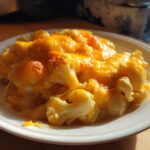 A close-up of a serving of Keto Cauliflower Mac and Cheese topped with melted, bubbly cheddar cheese.