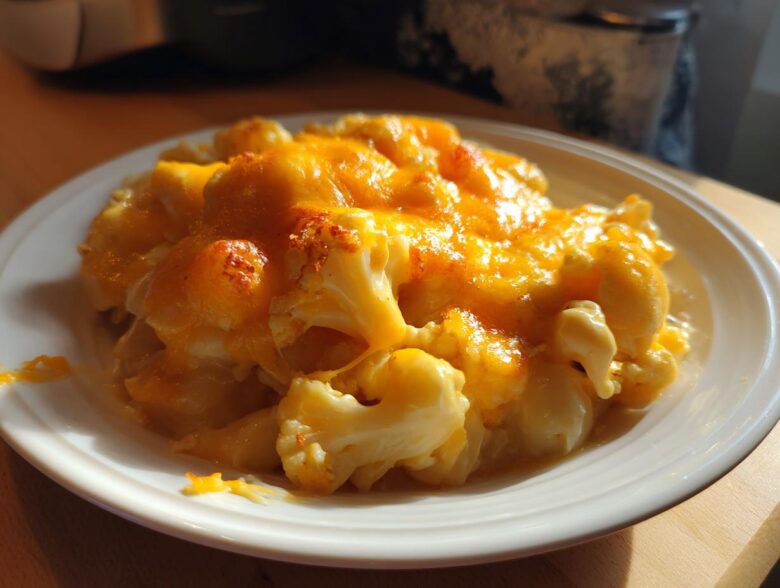 A close-up of a serving of Keto Cauliflower Mac and Cheese topped with melted, bubbly cheddar cheese.