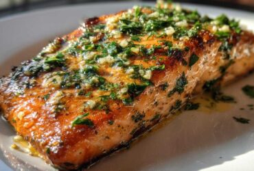Close-up of a perfectly cooked Keto Garlic Butter Salmon fillet topped with melted butter, minced garlic, and fresh parsley.