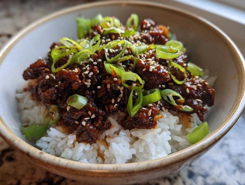 A close-up of Korean Ground Beef Bulgogi Bowls featuring savory ground beef over white rice, topped with green onions and sesame seeds.