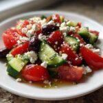 Close-up of a vibrant Mediterranean Cucumber Tomato Salad topped with crumbled feta cheese and Kalamata olives.