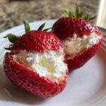 Two fresh strawberries halved and generously filled with creamy white No-Bake Cheesecake Stuffed Strawberries filling.