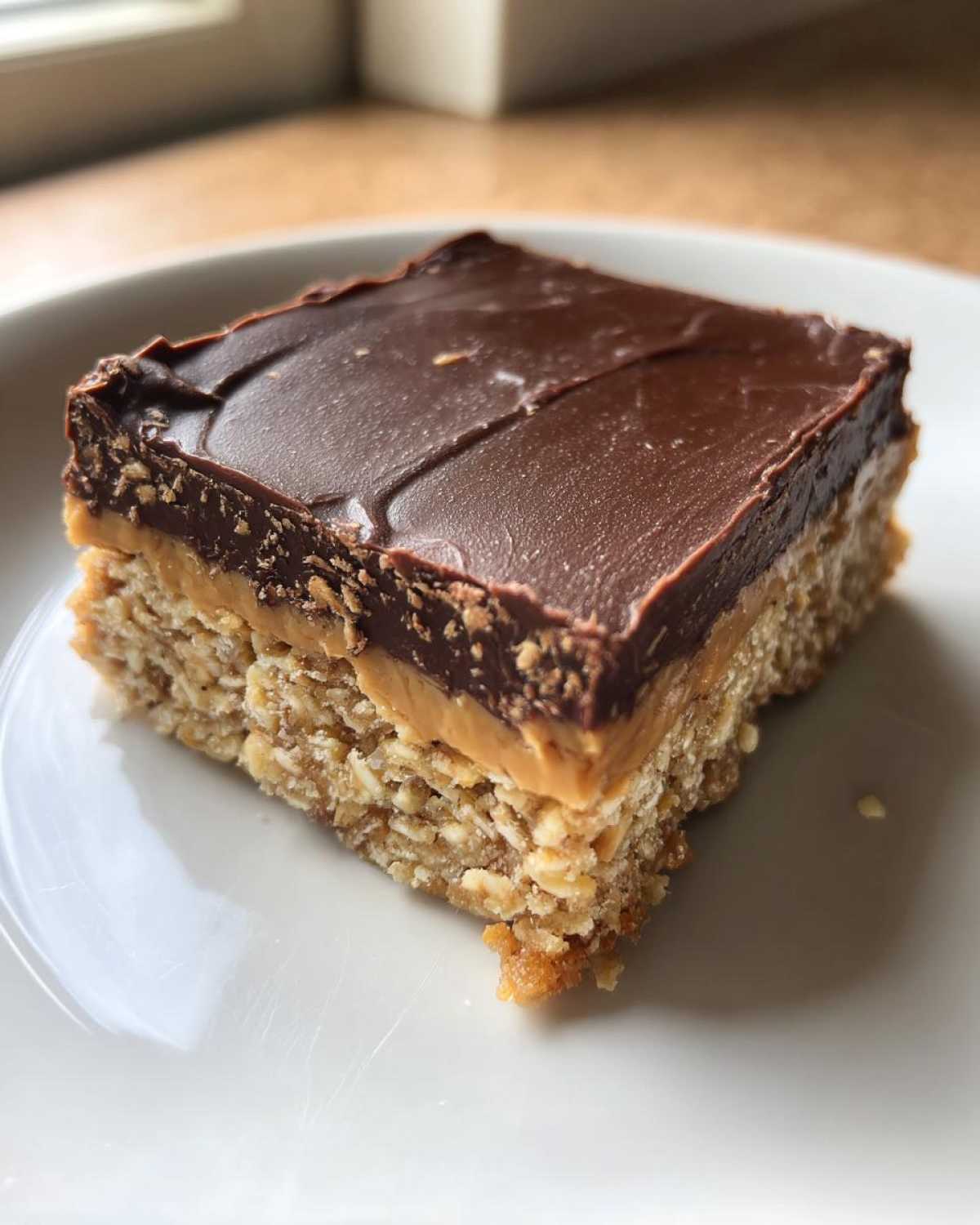 Close-up of a single square of No-Bake Chocolate Peanut Butter Oat Bars on a white plate.