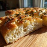 Close-up of a thick, airy slice of No-Knead Skillet Focaccia with Rosemary and coarse salt.