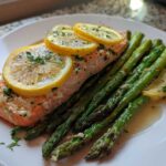 A serving of One-Pan Lemon Garlic Salmon with Asparagus topped with lemon slices and parsley.