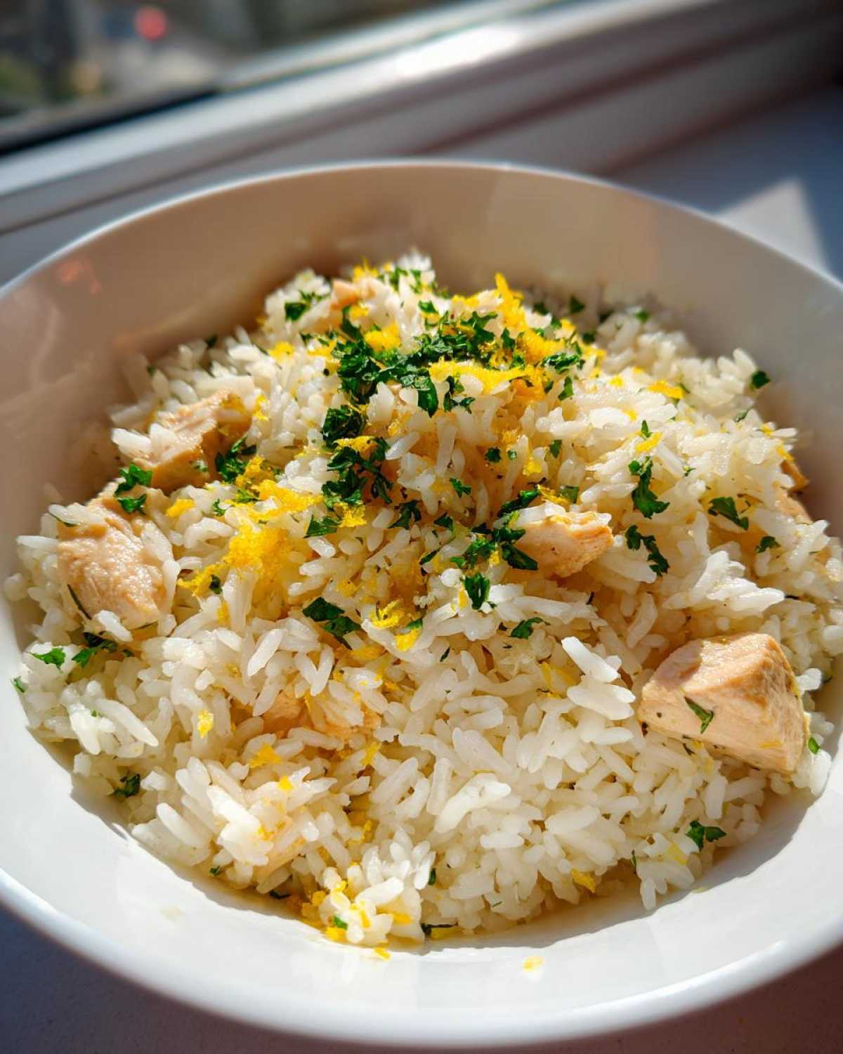 Close-up of One-Pot Chicken and Rice with Lemon and Herbs topped with bright lemon zest and parsley.