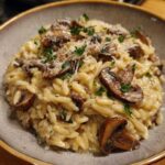 Close-up of creamy mushroom orzo topped with sautéed mushrooms, grated Parmesan, and fresh parsley.