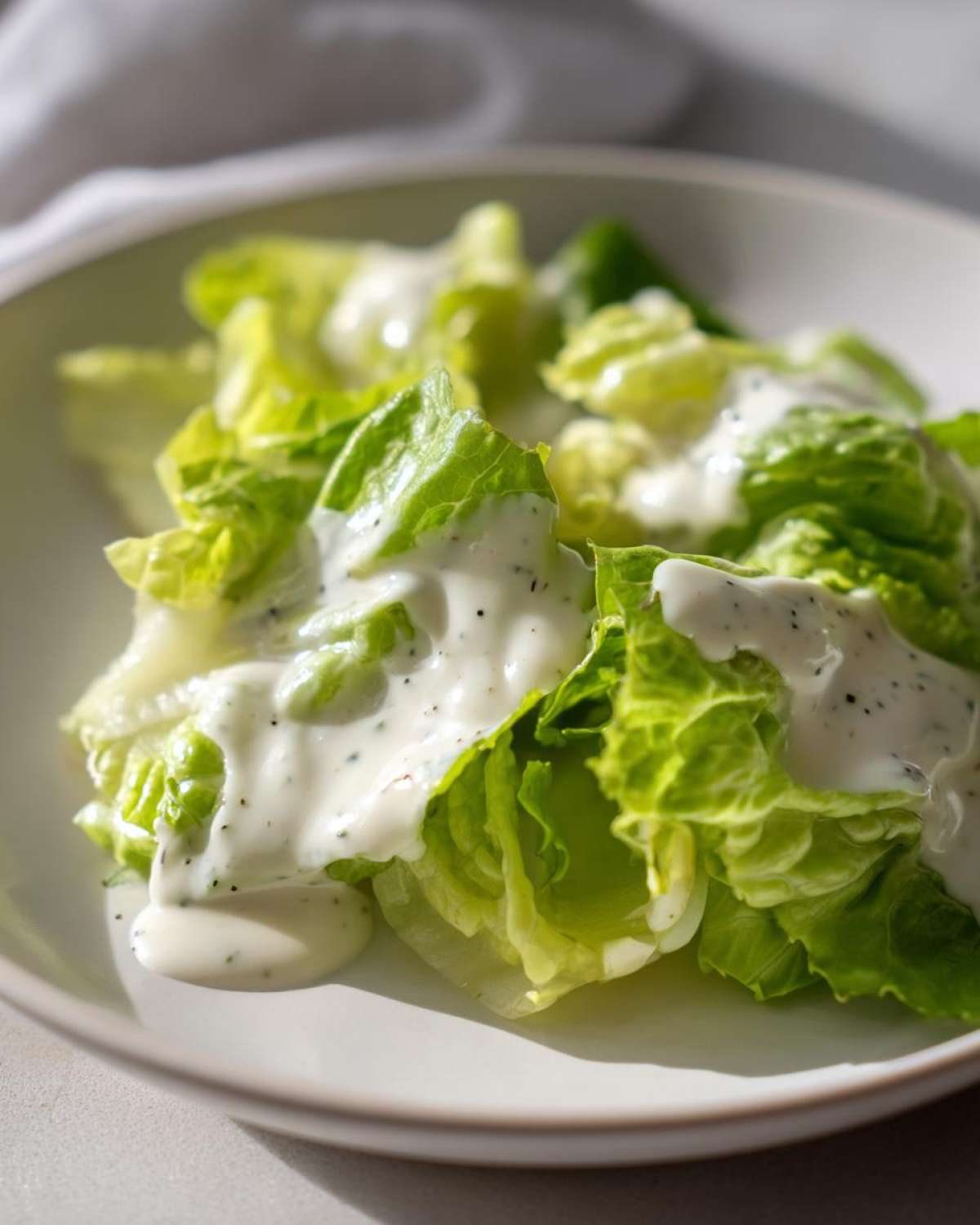 Close-up of crisp romaine lettuce tossed generously with creamy Copycat Olive Garden Salad Dressing.