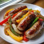 Close-up of perfectly browned sausages served with colorful roasted peppers and onions from Sheet Pan Sausage and Peppers.