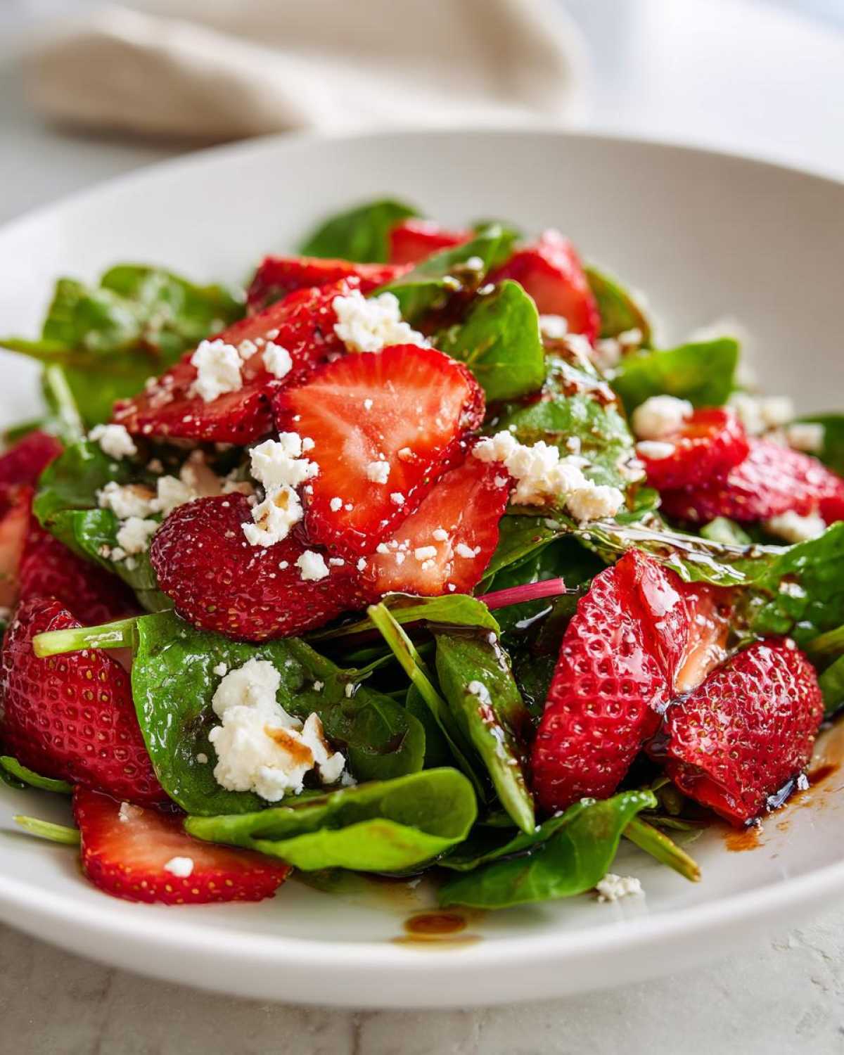 Close-up of a vibrant Spring Mix Salad with Strawberries and Goat Cheese, drizzled with balsamic glaze.