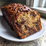 Close-up of a slice of moist Vegan Chocolate Banana Bread topped with chocolate chips.