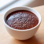 Close-up of rich Vegan Chocolate Chia Pudding topped with visible chia seeds in a white bowl.
