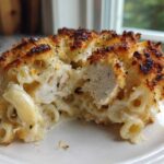 A close-up of Cheesy Baked Chicken Alfredo with Crispy Top, showing creamy pasta, chicken pieces, and a golden-brown crust.