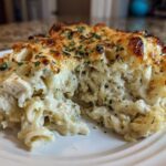 A serving of Cheesy Chicken Alfredo Bake showing creamy sauce, pasta, chicken, and a golden, bubbly cheese crust.