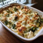 Close-up of a bubbling Cheesy Chicken and Broccoli Bake Comfort Dish topped with golden-brown melted cheese.