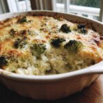A close-up of a baked Cheesy Chicken and Broccoli Bake Comfort Dish with a bubbly, golden-brown cheese crust and visible broccoli florets.