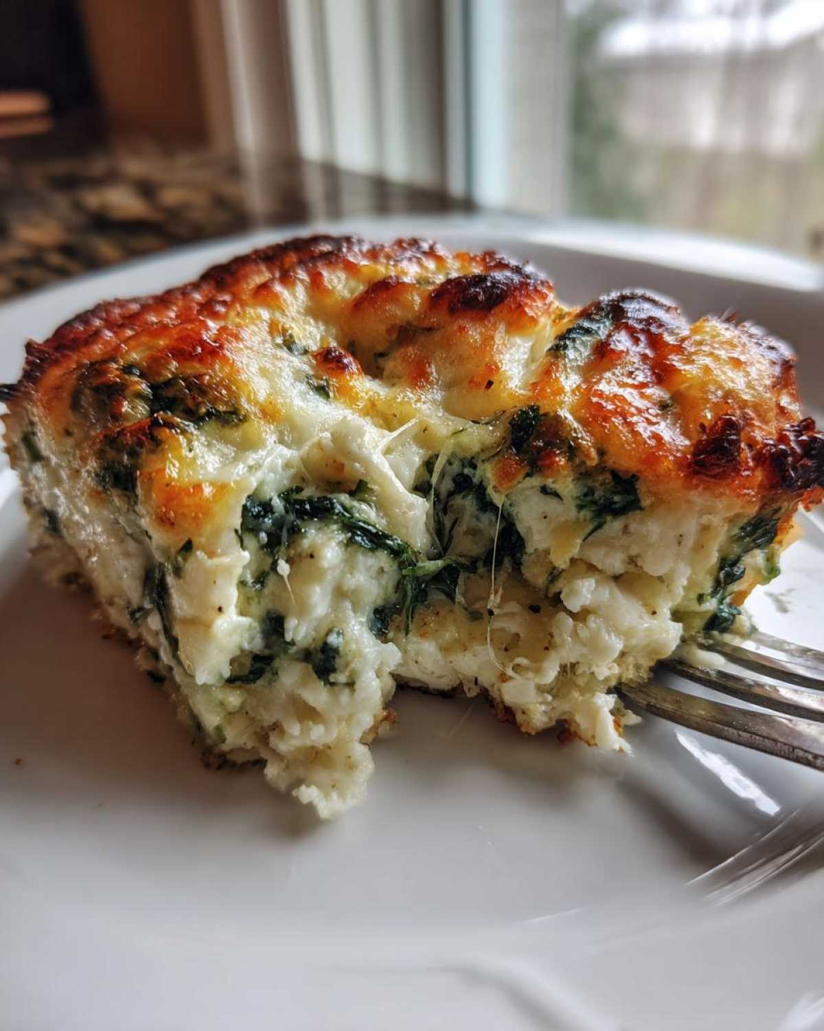 Close-up of a serving of Cheesy Chicken and Spinach Bake, showing melted cheese and spinach texture.