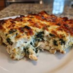 A generous slice of Cheesy Chicken and Spinach Bake Comfort Meal with a golden, bubbly cheese crust.