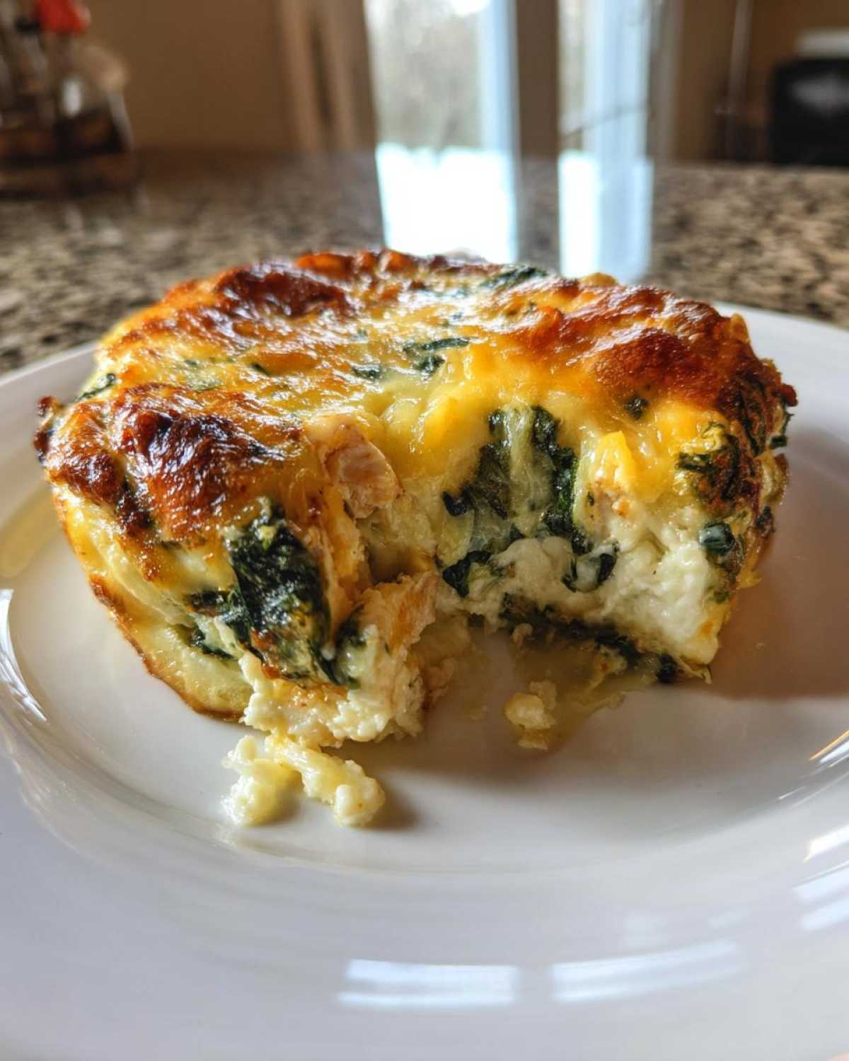 Close-up of an individual portion of Cheesy Chicken and Spinach Bake with a golden-brown top and creamy interior.