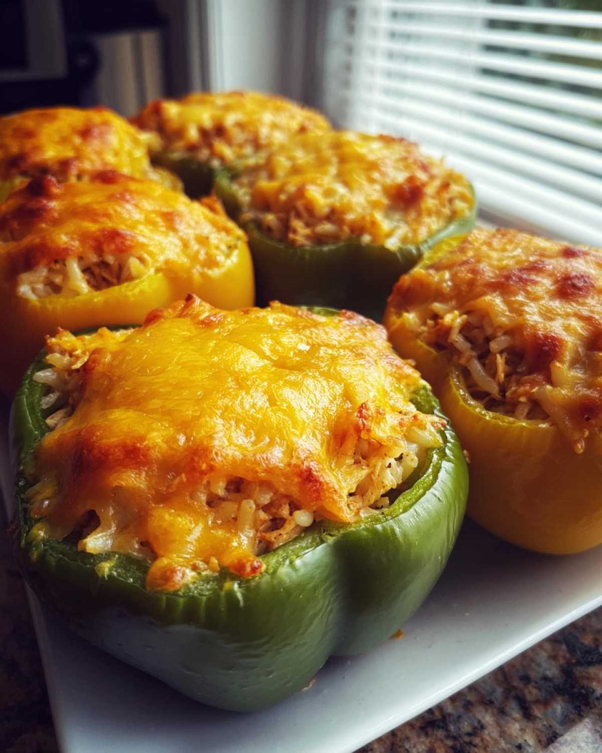 Close-up of baked Cheesy Chicken Stuffed Bell Peppers, topped with melted cheddar cheese.