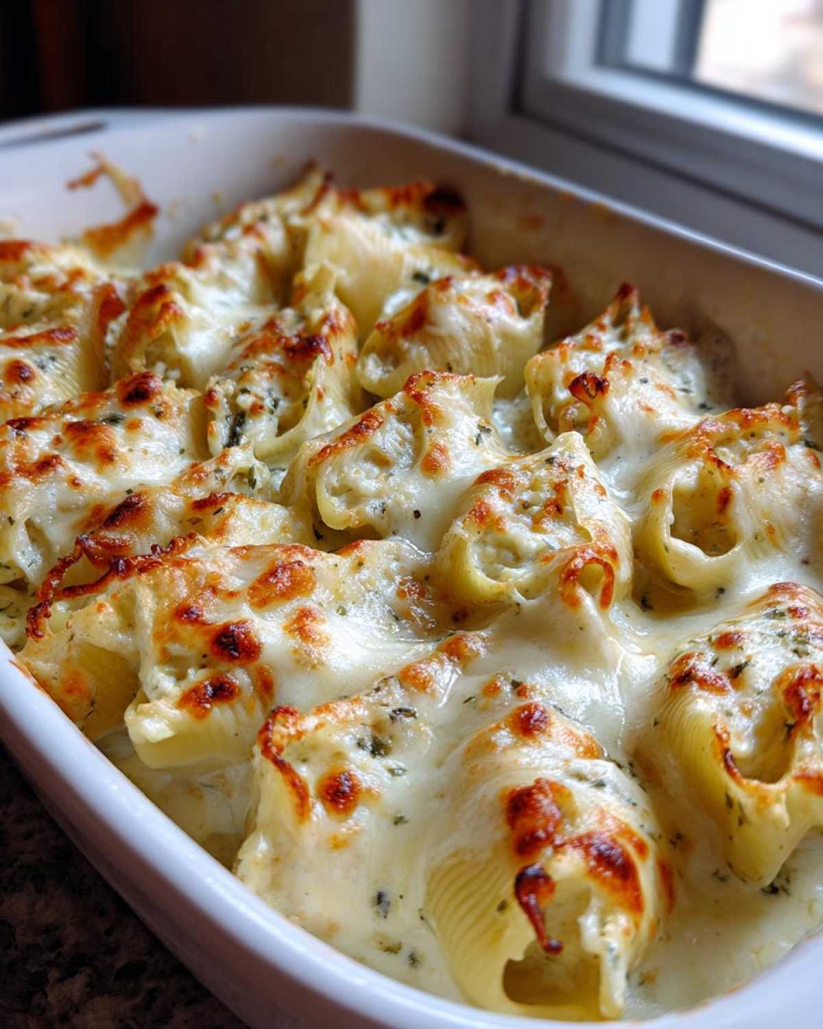Close-up of baked Cheesy Chicken Stuffed Pasta shells covered in bubbling, browned cream sauce.