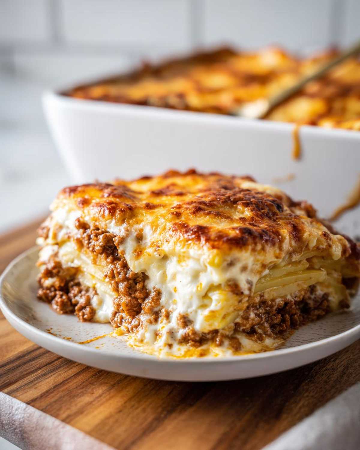 A thick, layered slice of Cheesy Ground Beef and Potato Bake with a golden, bubbly cheese topping.