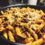 Close-up of Cheesy Ground Beef Pasta Skillet with melted cheddar and mozzarella over penne pasta and seasoned ground beef.
