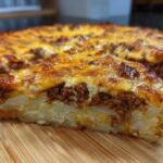 A close-up of a slice of Cheesy Ground Beef and Potato Bake Comfort Food showing layers of potatoes, meat, and melted cheese.